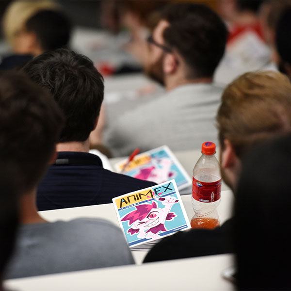 Students in a lecture theatre. One is holding an Animex brochure