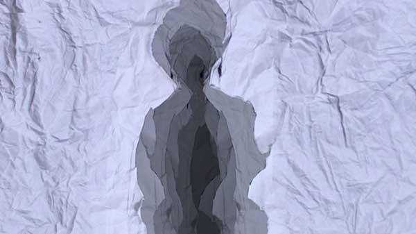 A crumpled paper backdrop is holding a multiple layered silhouette that resembles a person
